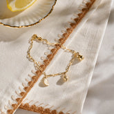 Yellow gold miniature citrus wedge, lemon, and pear jewellery charms on a yellow gold paper clip chain.